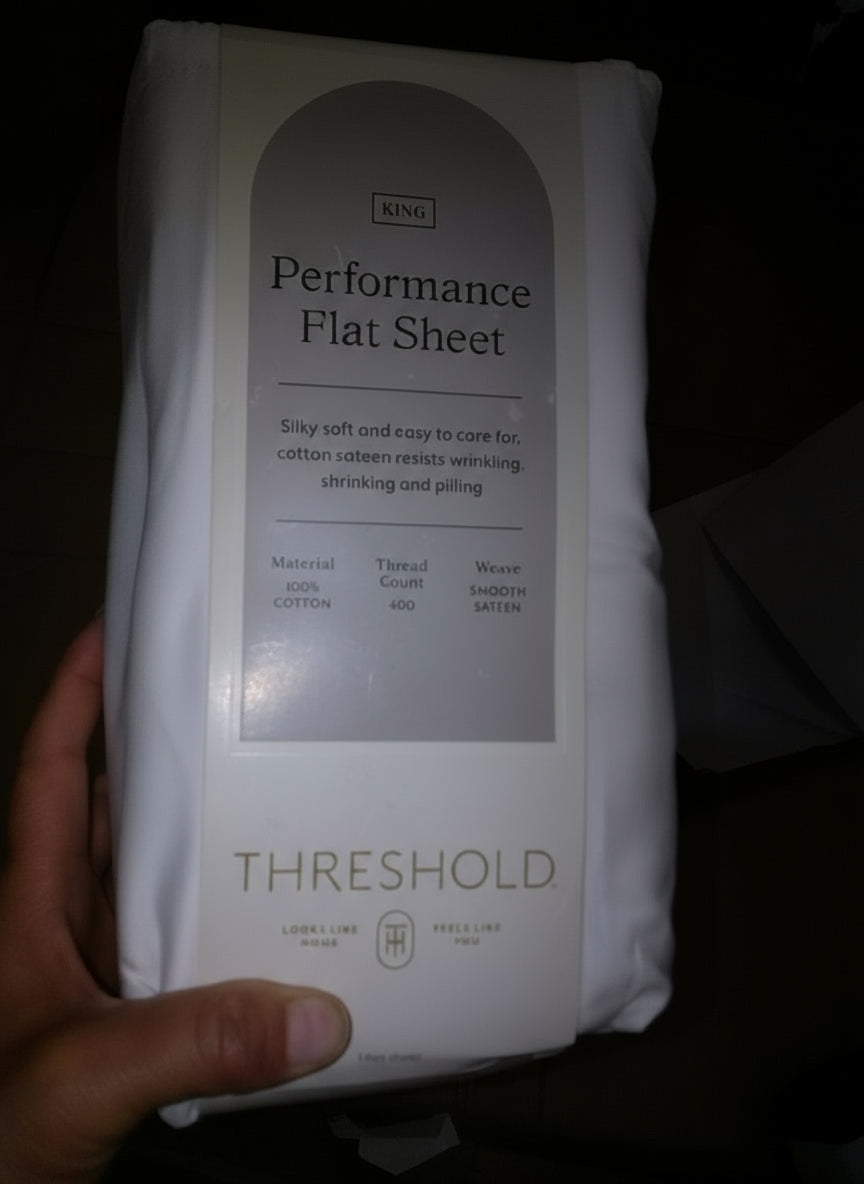 Threshold Performance Flat Sheet packaging held by a hand on a dark background