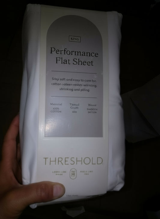 Threshold Performance Flat Sheet packaging held by a hand on a dark background